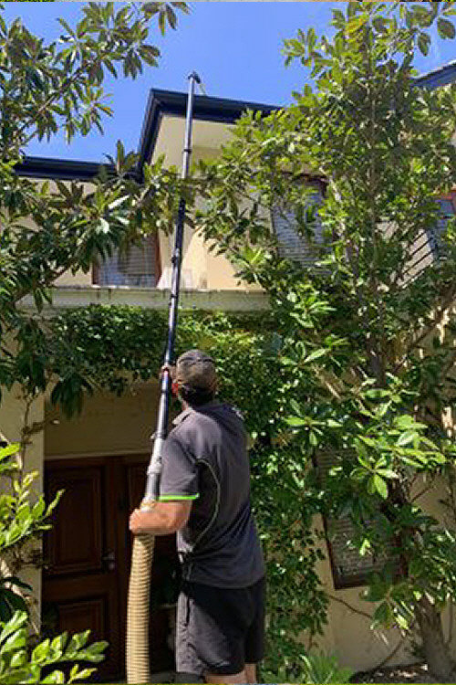 Photo of extended gutter cleaning unit with long pole extension, working on 2 story house